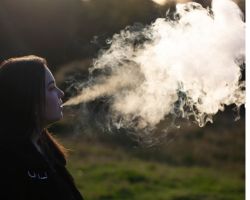 A woman exhaling a large cloud of vapour.